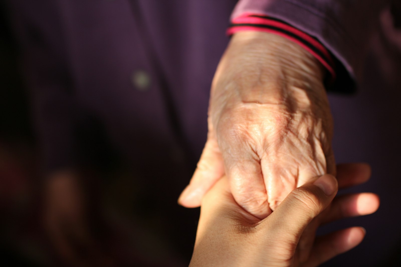 Eine jüngere Hand hält die Hand einer älteren Person
